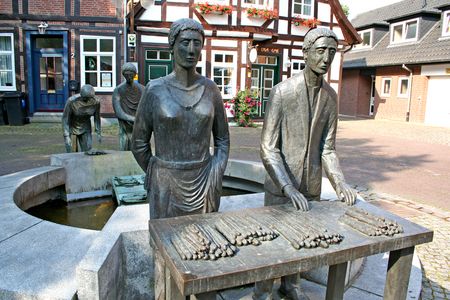 Bronzestatue einer Spargelerntetruppe in Nienburg, die stolz den Nienburger Spargel präsentiert.