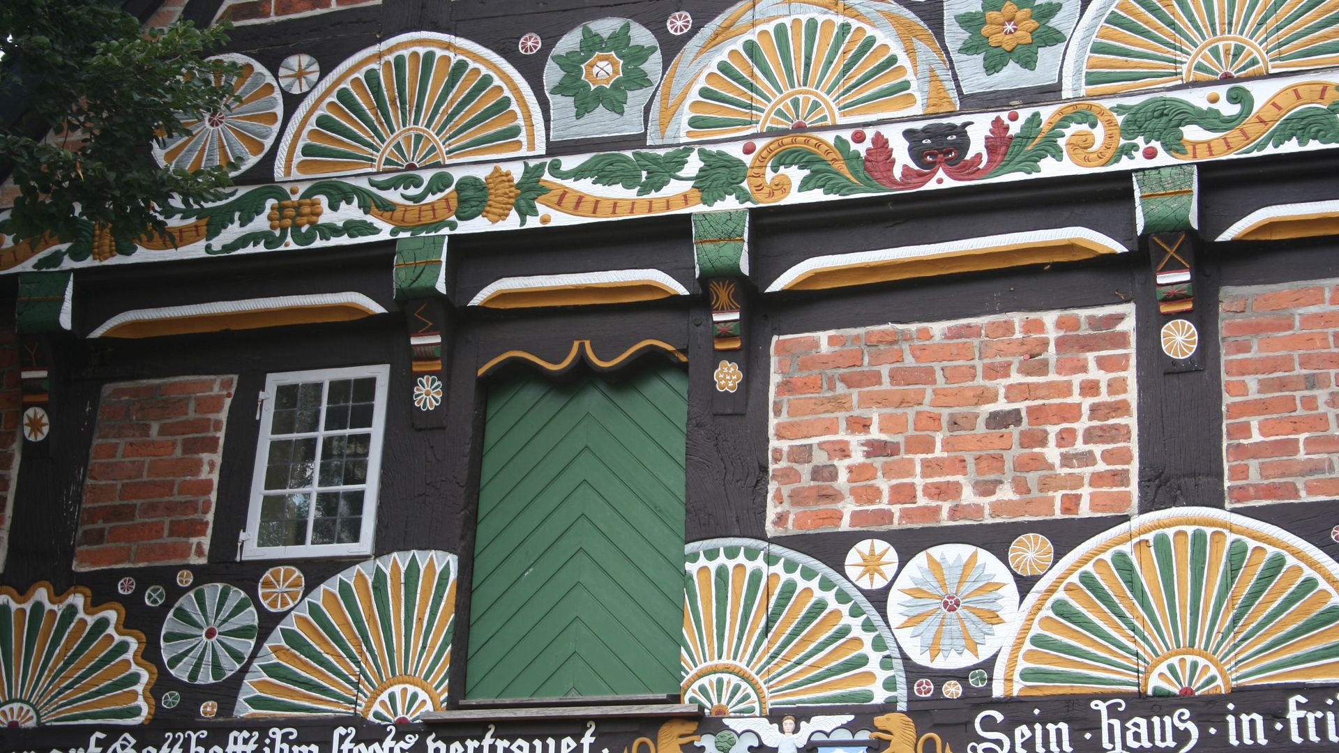 Fachwerkfassade eines historischen Ackerbürgerhauses in Verden, reich verziert mit buntem Schnitzwerk.