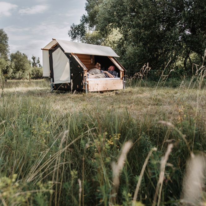 Zwei Personen liegen im Bett to Go in der Natur im destinature Dorf Hitzacker.