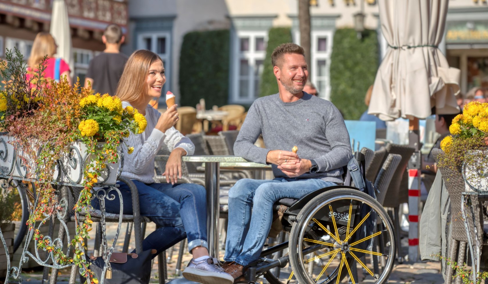 A couple, the man sitting in a wheelchair, enjoying an ice cream in the sun., © TMN/ Christian Bierwagen