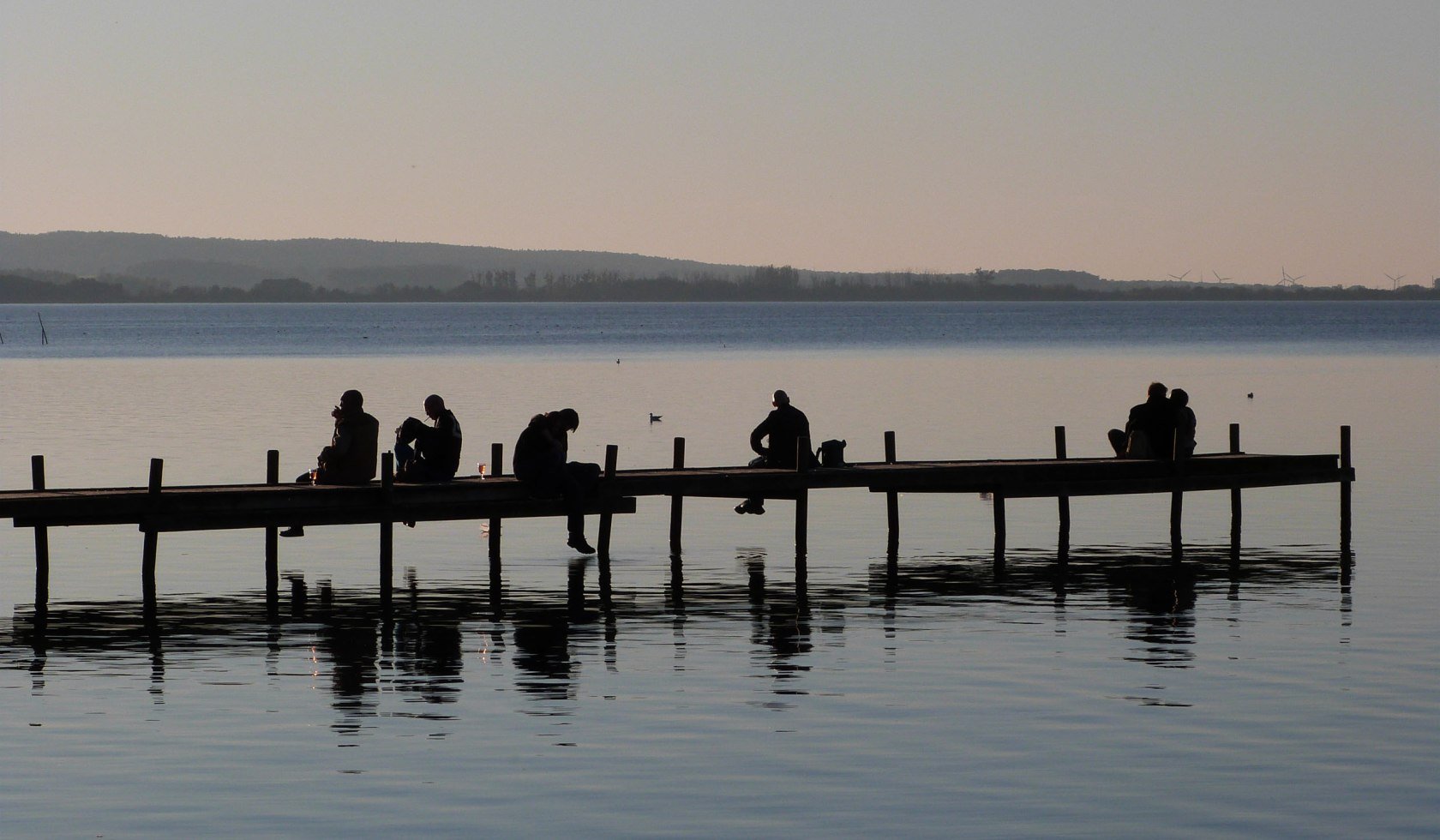 People sitting on a jetty in Steinhude in the evening light, © Steinhuder Meer Tourismus GmbH / F. Toffel