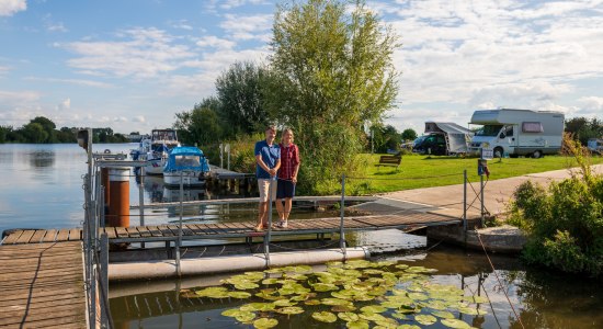 A couple standing on a jetty by the river Weser, with a camper van site in the background., © TMN / Markus Tiemann