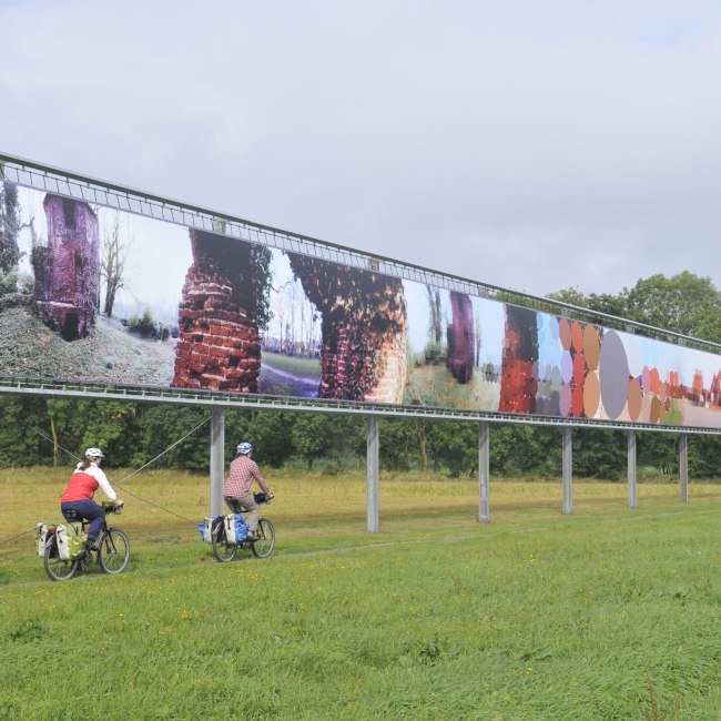 Three cyclists pass an art object, © TMN / Thorsten Brönner