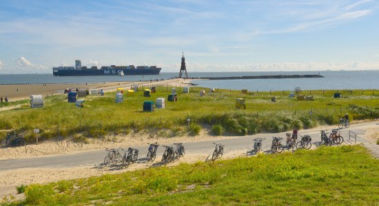 Landscape on the Elbe near Cuxhaven-Döse with Kugelbake, container ship, bicycles and beach chairs., © TMN/Dieter Schinner